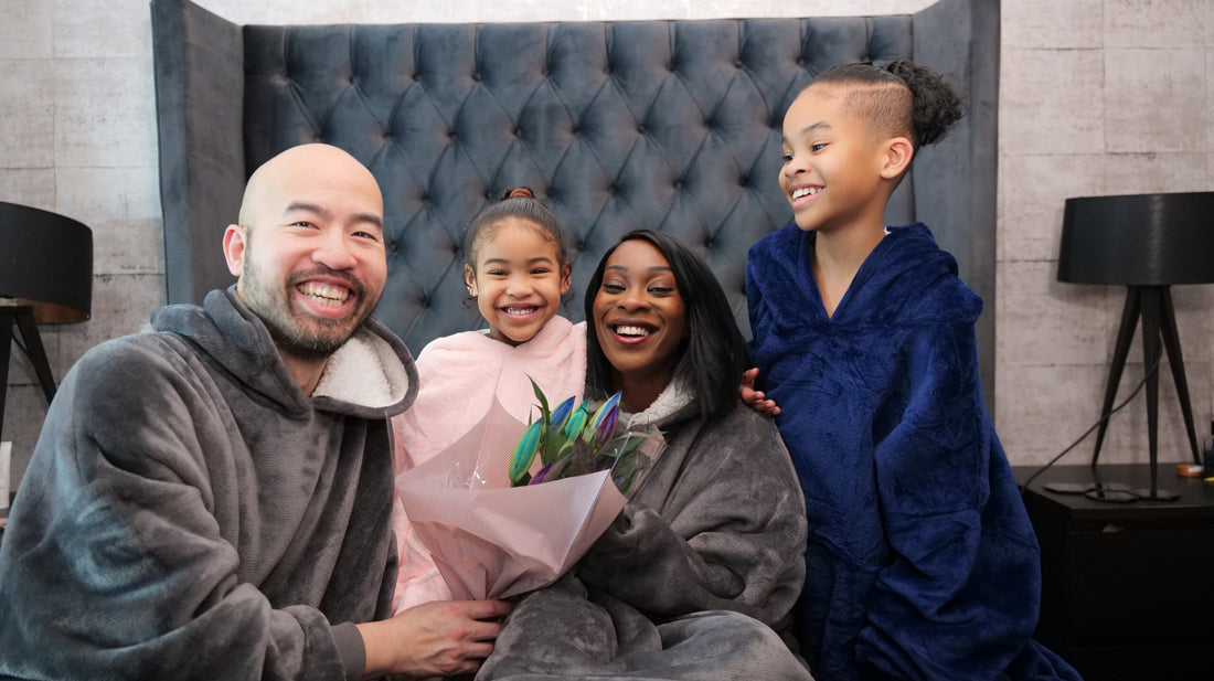 Family smiling at camera wearing hoodie blankets